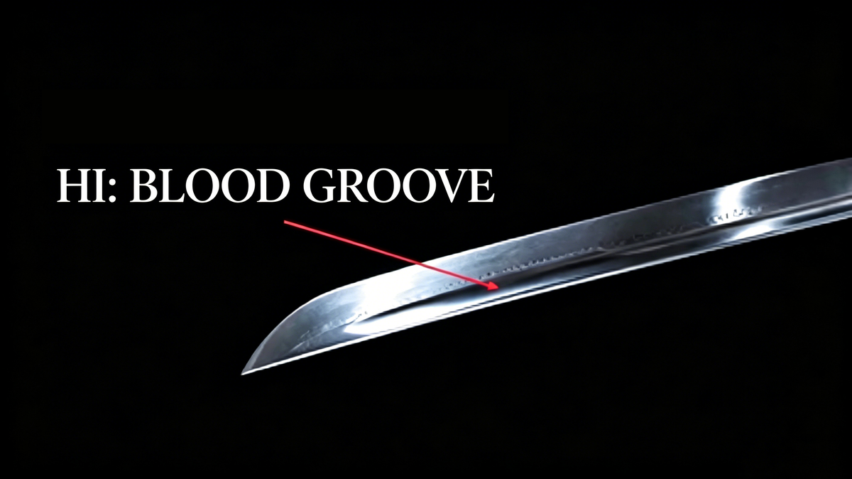 Close‑up studio shot of polished katana blade with annotated hi blood groove against solid black background, nihonto detail photograph