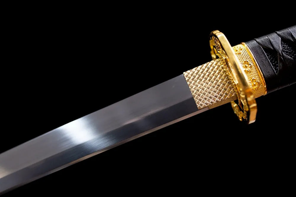 Upper polished 1060‑steel tachi blade brass habaki smooth steel surface macro close‑up