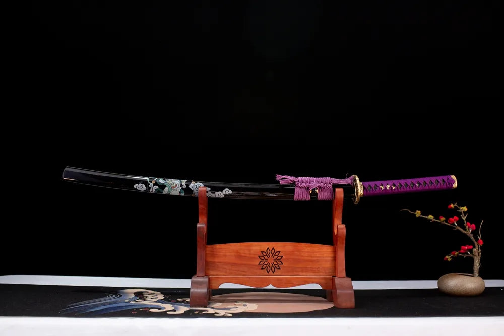 Horizontal laid closed glossy‑black painted raijin‑fujin Raijin‑Fujin‑Katana scabbard flat table‑top front display