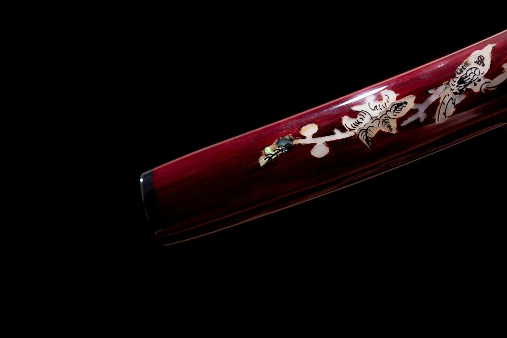 Bottom off‑white gold‑crane‑maki‑e saya antique‑brass kojiri end‑cap close‑up