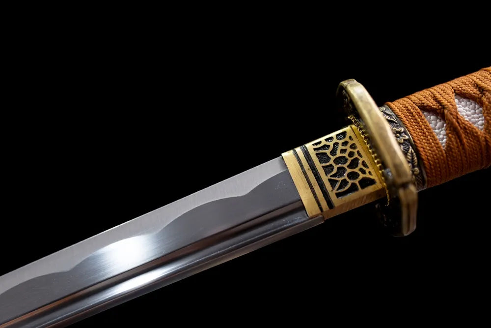 Upper T10 clay‑tempered steel blade brass habaki suguha hamon temper‑line macro close‑up