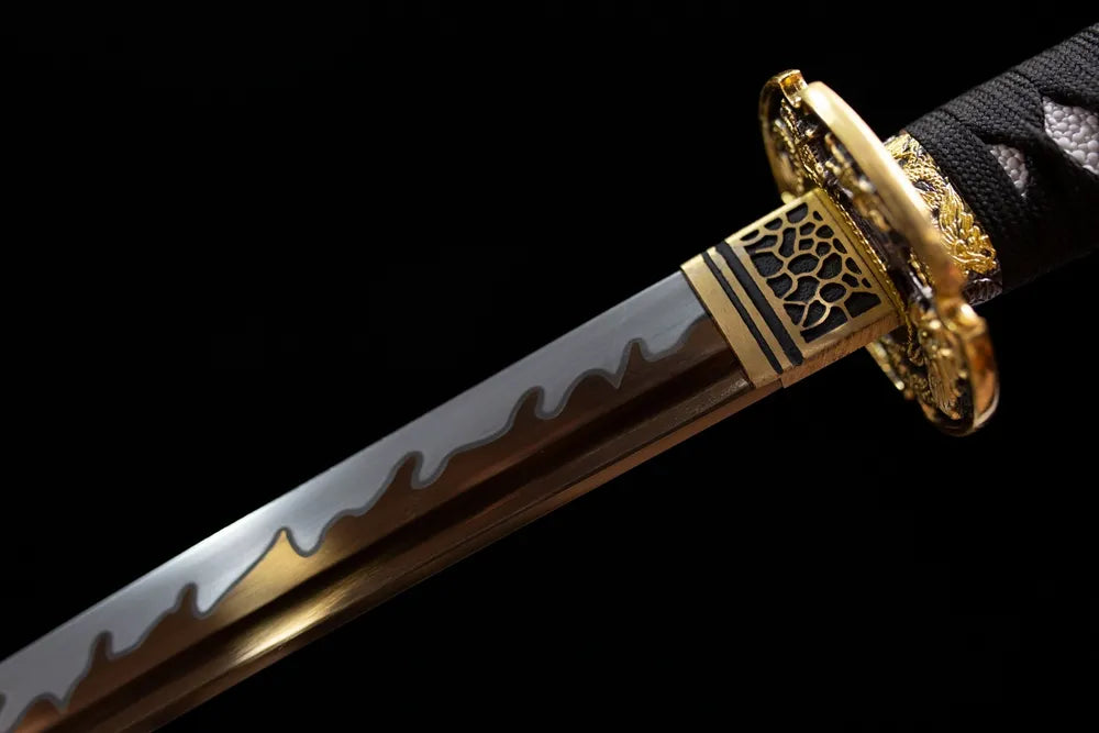 Upper T10 clay‑tempered tachi blade brass habaki wave‑pattern hamon temper‑line macro close‑up