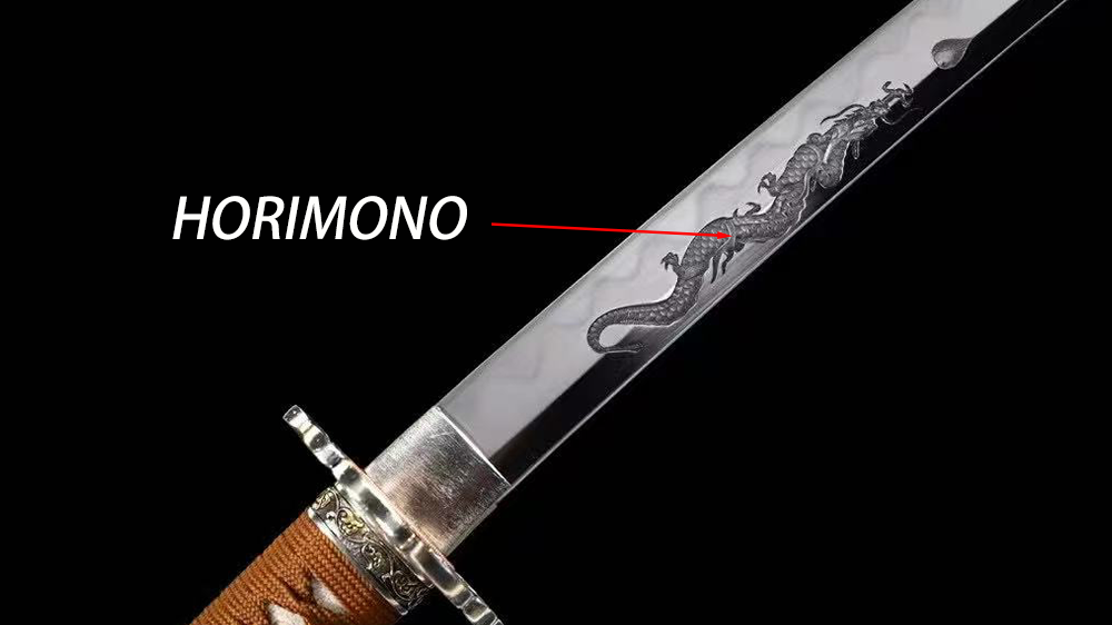 Close‑up photograph of katana blade engraved with dragon horimono carving, labeled diagram pointing to sword horimono detail, dark studio background