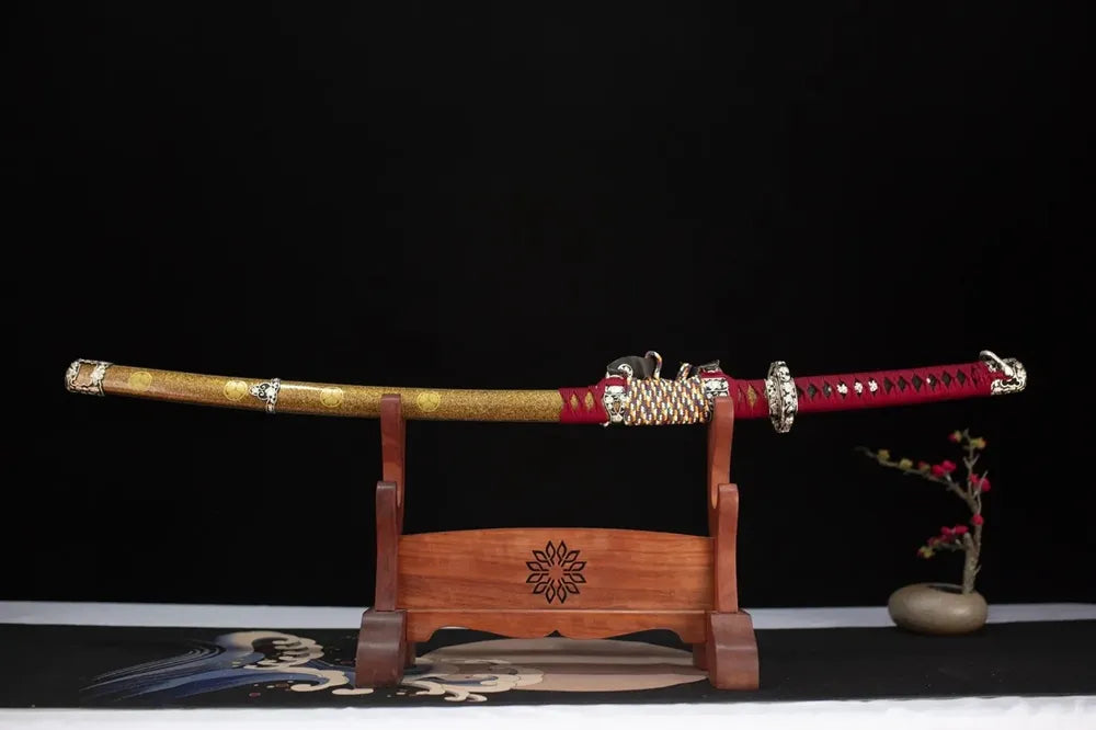 Horizontal laid closed golden‑grain kamon‑emblem Perseverance‑Tachi scabbard flat table‑top front display