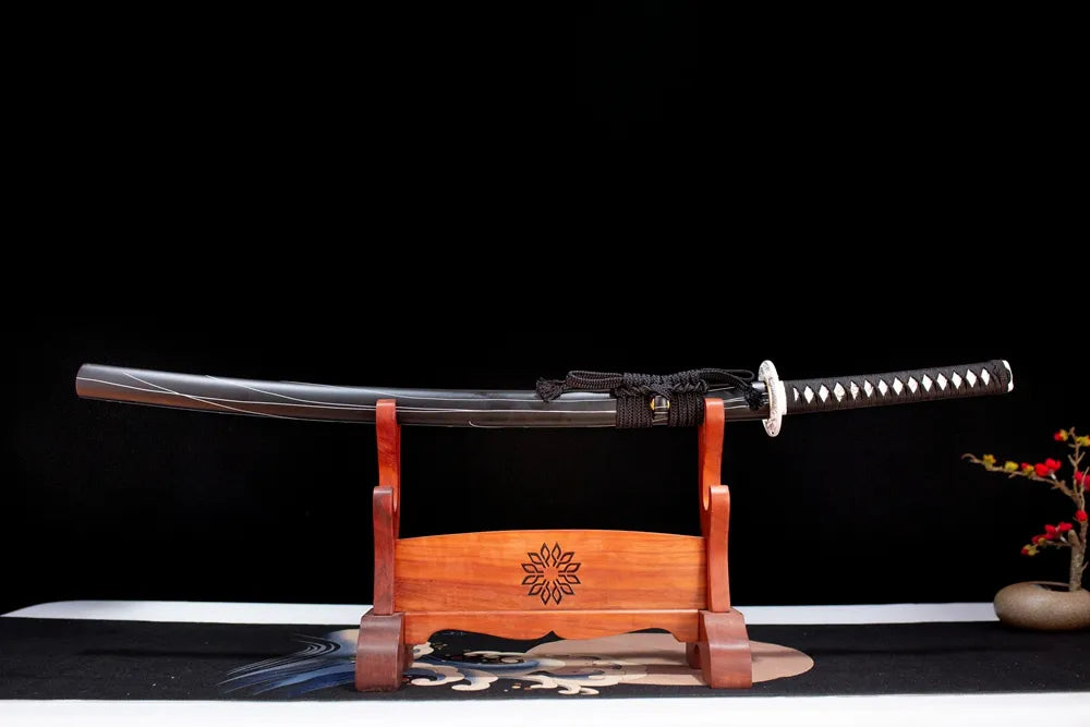 Horizontal laid closed raven‑black dusky‑purple‑phantom‑butterfly Melanitis‑Katana scabbard flat table‑top front display