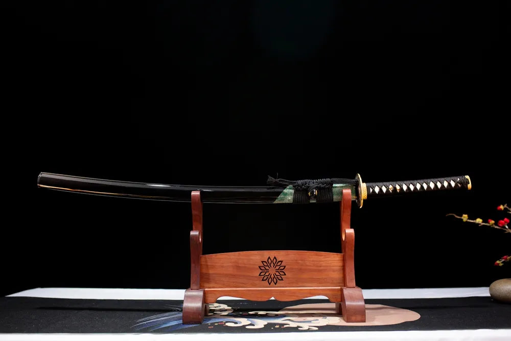 Horizontal laid closed glossy‑black partial green fish‑skin overlay May‑Katana scabbard flat table‑top front display