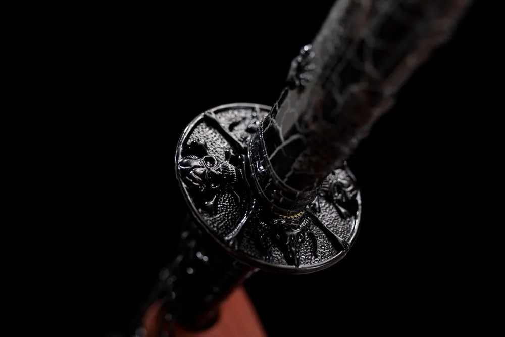 Reverse‑side skull‑ornament dark‑alloy tsuba surface texture close‑up