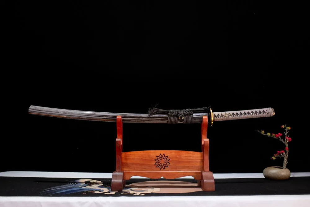 Horizontal laid closed charcoal‑black natural wood‑grain Tiankui‑Katana scabbard flat table‑top front display