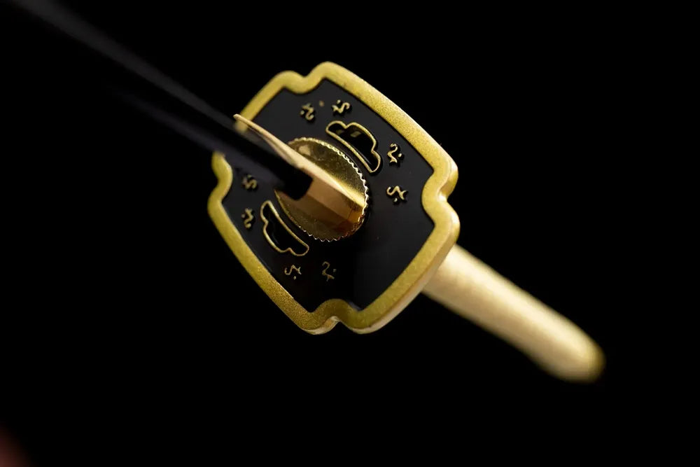 Front engraved‑symbol golden‑alloy legacy‑theme demon‑slayer hand‑guard close‑up