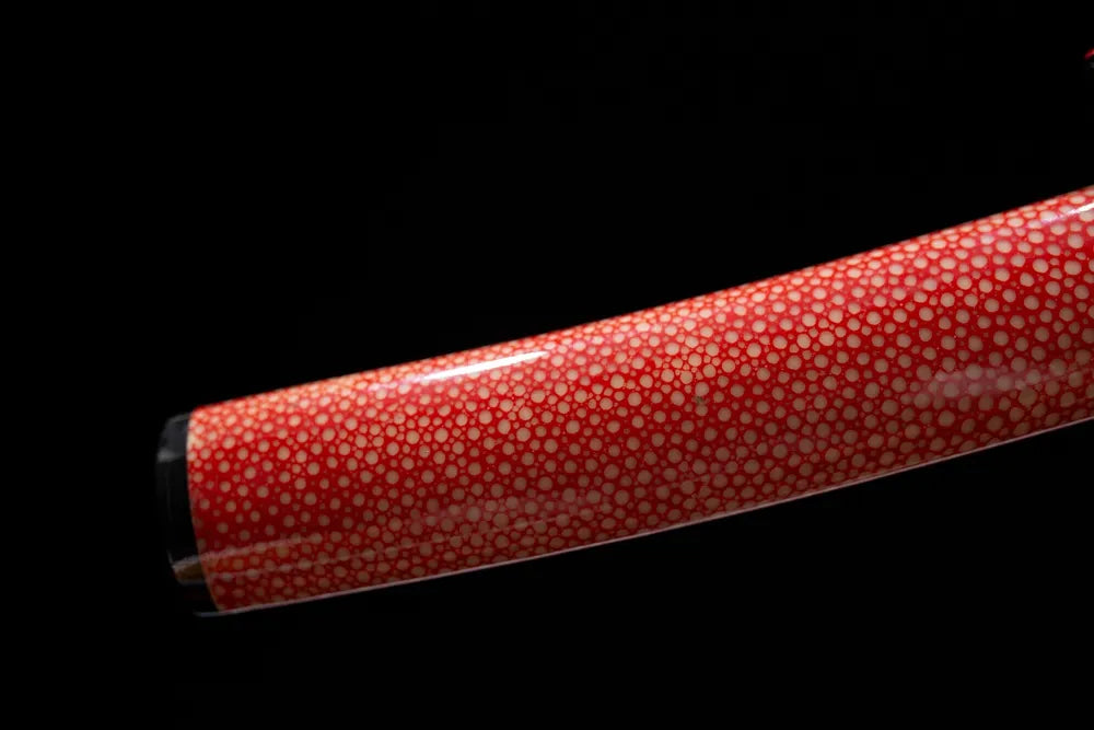 Bottom red faux‑ray‑skin maki‑e saya black‑gold gilded kojiri end‑cap close‑up