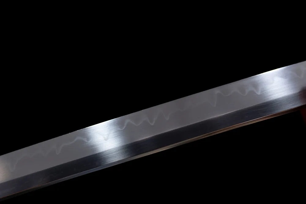 Mid‑section irregular gunome‑style undulating hamon steel katana blade surface close‑up shot