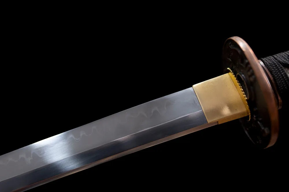 Upper T10 clay‑tempered katana blade brass habaki natural irregular hamon temper line macro close‑up