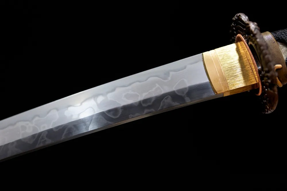 Upper T10 clay‑tempered wakizashi blade brass habaki notare flowing undulating hamon temper‑line macro close‑up