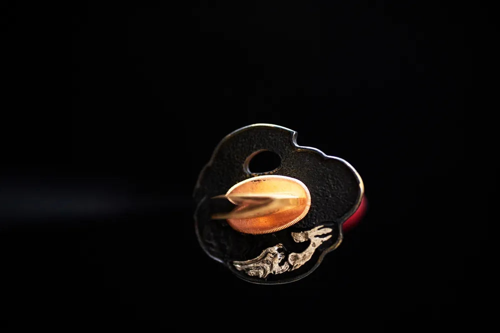 Front open‑work red‑plum‑floral‑relief black‑gold gilded wakizashi hand‑guard close‑up