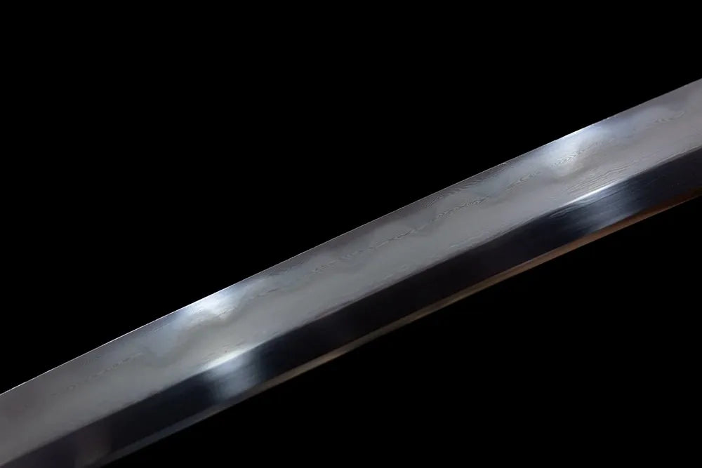 Upper T10 clay‑tempered tachi blade brass habaki natural hamon temper‑line macro close‑up